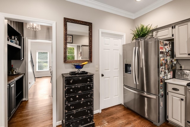 kitchen featuring a toaster, a notable chandelier, crown molding, wood finished floors, and stainless steel fridge with ice dispenser