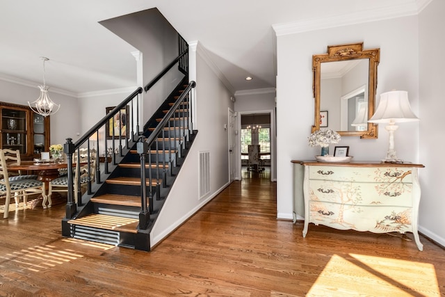 stairs with a chandelier, ornamental molding, wood finished floors, and visible vents