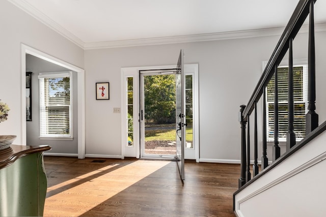 foyer featuring wood finished floors, crown molding, baseboards, and stairs