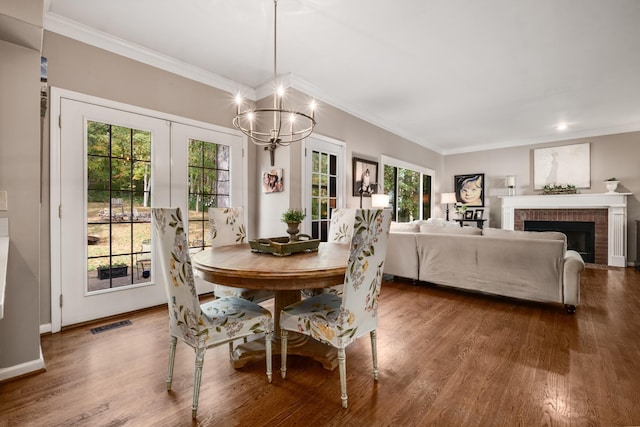 dining area with ornamental molding, visible vents, a fireplace, and wood finished floors