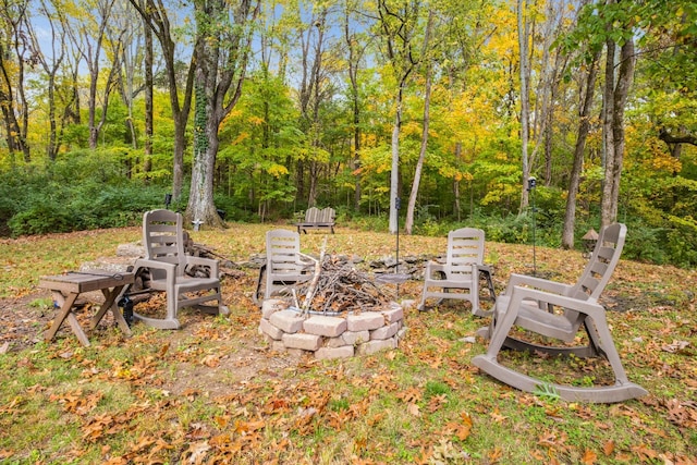 view of yard featuring an outdoor fire pit and a wooded view