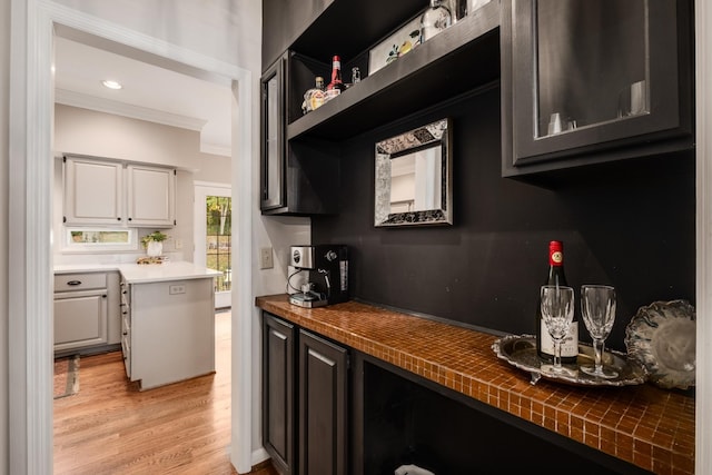 kitchen with ornamental molding, glass insert cabinets, light wood-style flooring, and recessed lighting