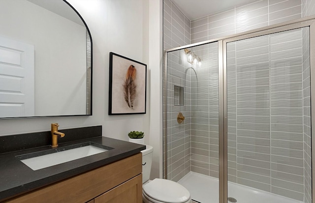 bathroom with toilet, a stall shower, and vanity