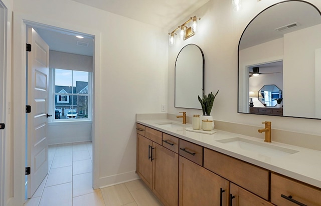 bathroom featuring double vanity, tile patterned flooring, a sink, and baseboards