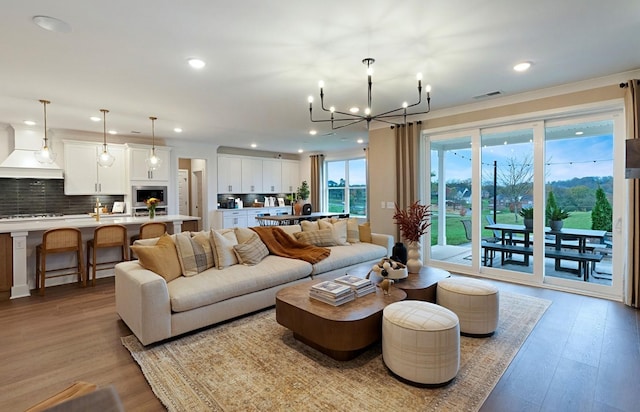 living area featuring recessed lighting, visible vents, light wood finished floors, and an inviting chandelier