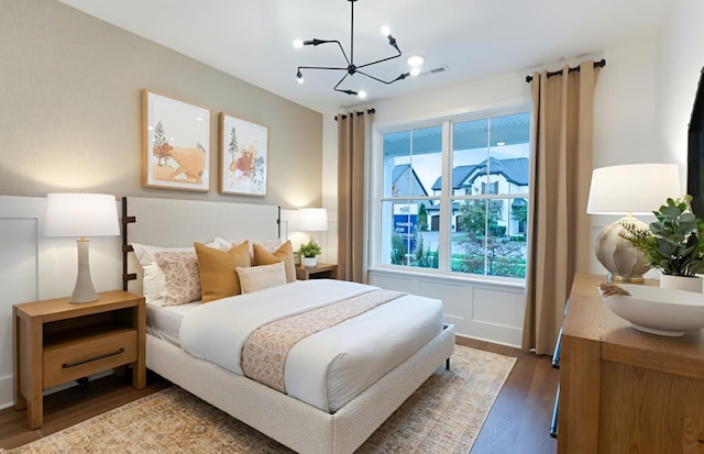 bedroom with visible vents, a notable chandelier, and wood finished floors