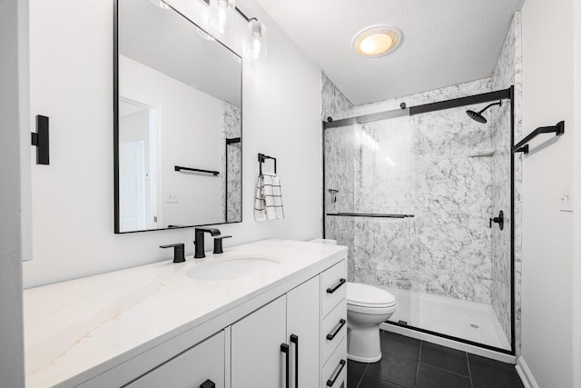 bathroom with a stall shower, vanity, toilet, and tile patterned floors