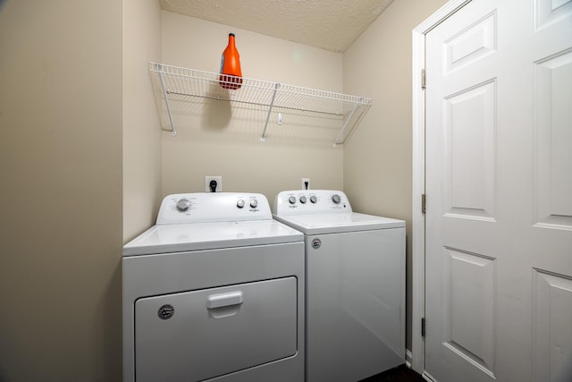 clothes washing area with a textured ceiling, laundry area, and separate washer and dryer