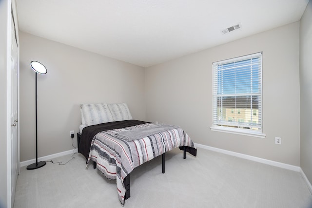 bedroom featuring visible vents, light carpet, and baseboards