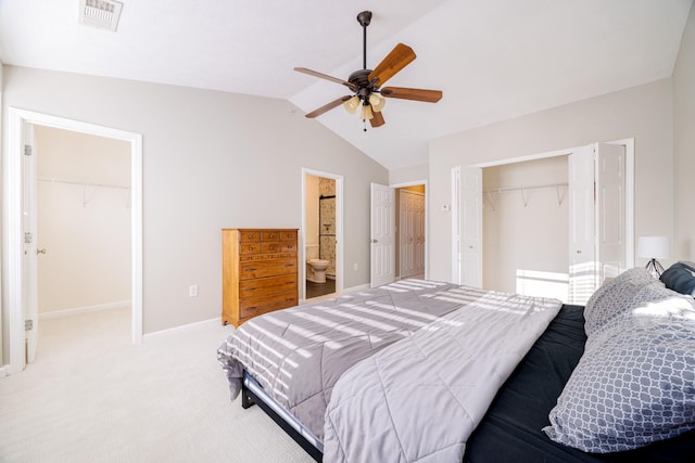 bedroom with visible vents, light colored carpet, a walk in closet, vaulted ceiling, and a closet