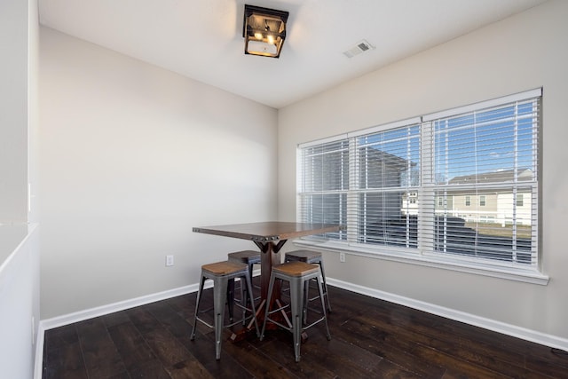 dining room featuring wood-type flooring, visible vents, and baseboards