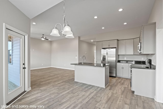 kitchen with stainless steel appliances, dark countertops, a sink, and light wood-style flooring