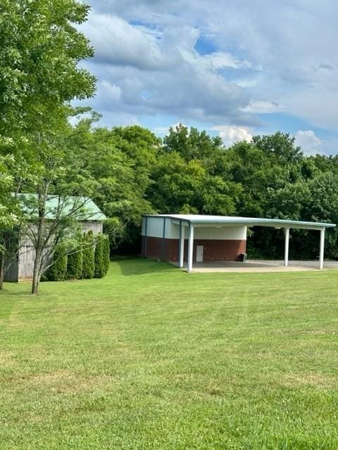 view of community with a carport, an outdoor structure, a lawn, and an outbuilding