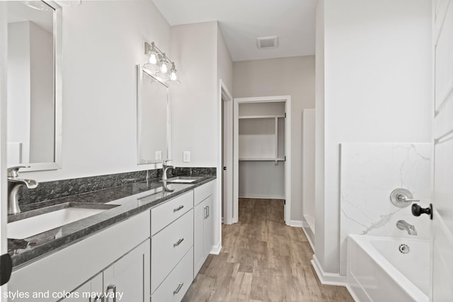 bathroom with a washtub, visible vents, a sink, and wood finished floors