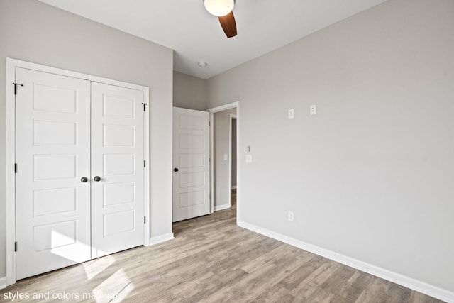 unfurnished bedroom featuring light wood-style floors, a ceiling fan, baseboards, and a closet