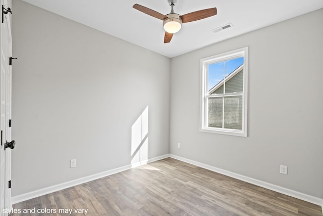 spare room featuring visible vents, wood finished floors, a ceiling fan, and baseboards