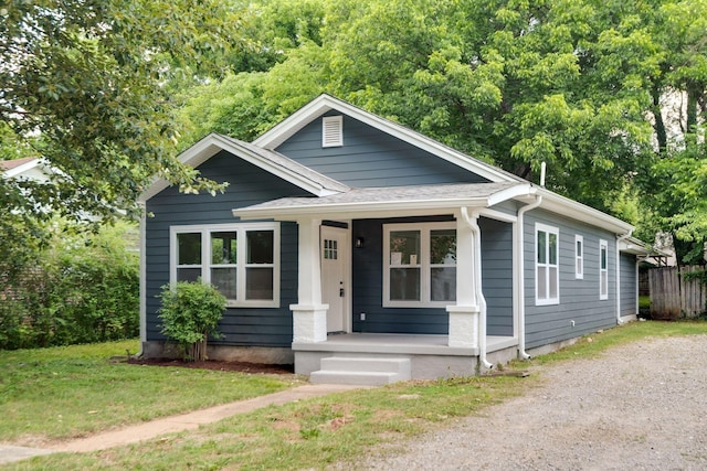 bungalow-style house featuring driveway, a shingled roof, a front lawn, and a porch