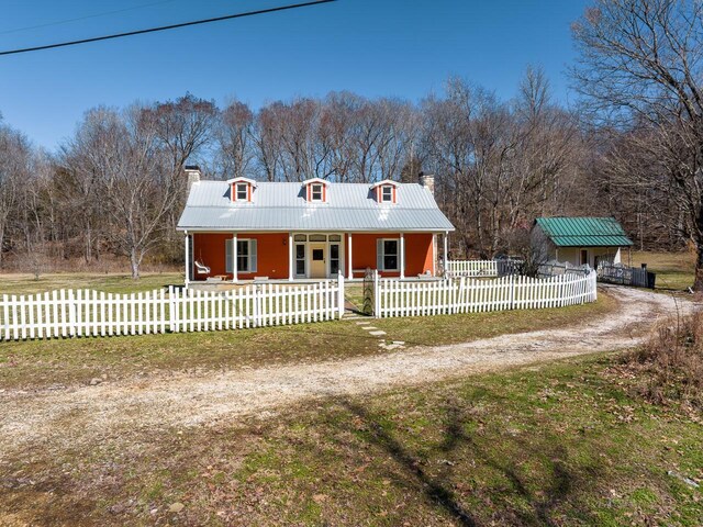 view of front facade with covered porch, metal roof, a chimney, and a fenced front yard