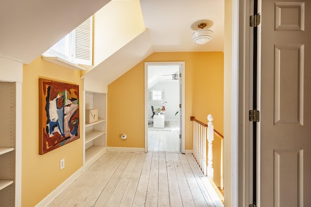 additional living space with vaulted ceiling, light wood-style flooring, and baseboards