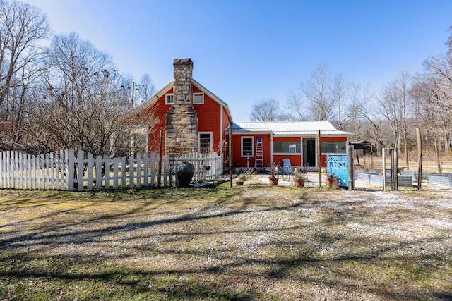 exterior space featuring metal roof, a chimney, and fence