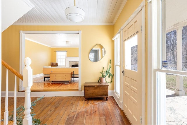 entrance foyer featuring baseboards, wood-type flooring, a fireplace, and crown molding