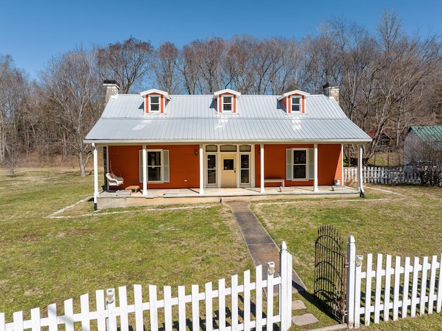 country-style home with a porch, metal roof, a chimney, and a fenced front yard