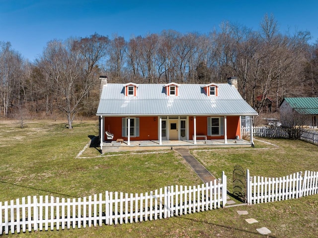 view of front facade featuring a fenced front yard, a chimney, metal roof, covered porch, and a front yard