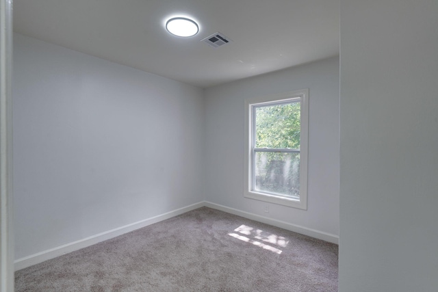 carpeted spare room featuring visible vents and baseboards