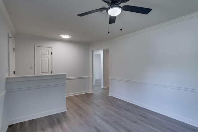 empty room featuring ceiling fan, crown molding, baseboards, and wood finished floors