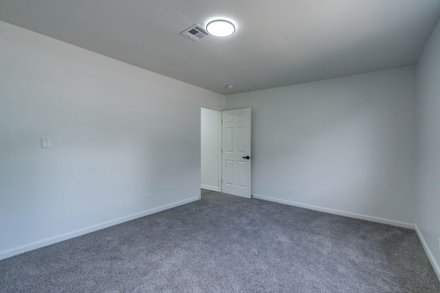 unfurnished room featuring dark colored carpet, visible vents, and baseboards