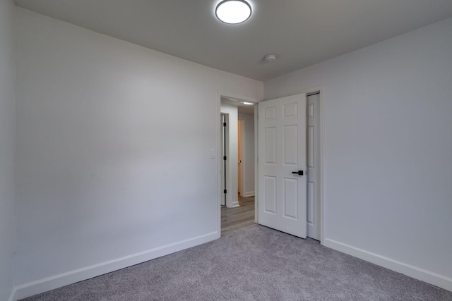 unfurnished room featuring light carpet and baseboards