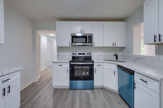 kitchen featuring appliances with stainless steel finishes, white cabinetry, a sink, and light stone counters