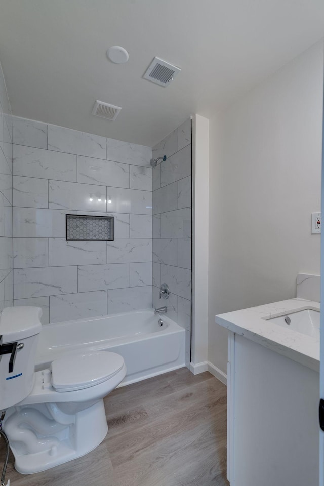 bathroom with visible vents, toilet, washtub / shower combination, vanity, and wood finished floors