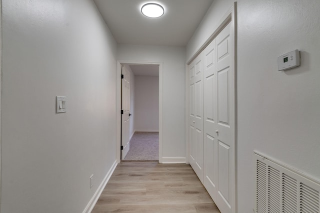 hallway featuring baseboards, visible vents, and light wood-style floors