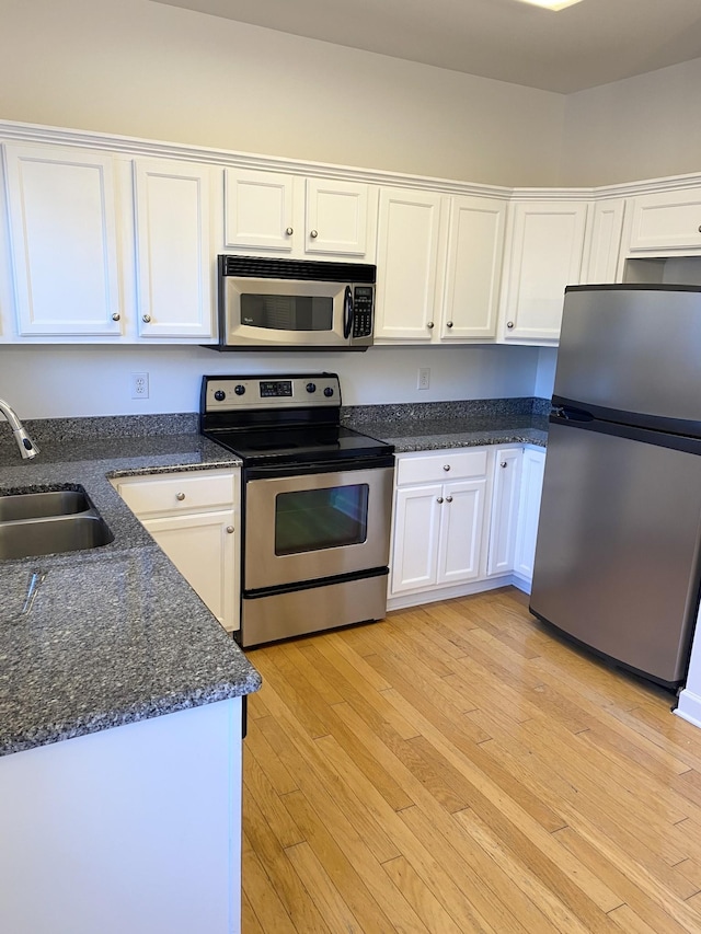 kitchen with appliances with stainless steel finishes, white cabinetry, and a sink