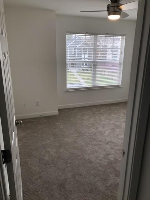 empty room with carpet floors, baseboards, and a ceiling fan