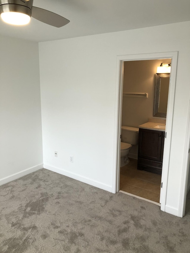 unfurnished bedroom with ensuite bathroom, carpet floors, and baseboards