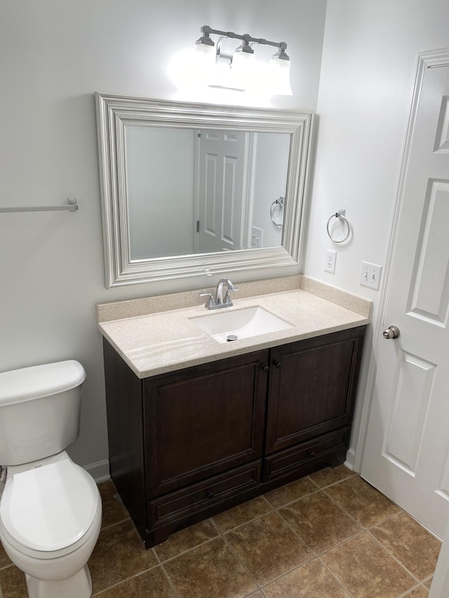 bathroom with toilet, baseboards, vanity, and tile patterned floors