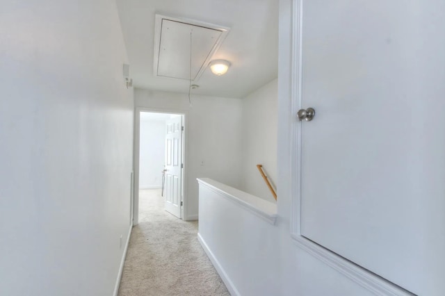 hall with attic access, baseboards, light colored carpet, and an upstairs landing