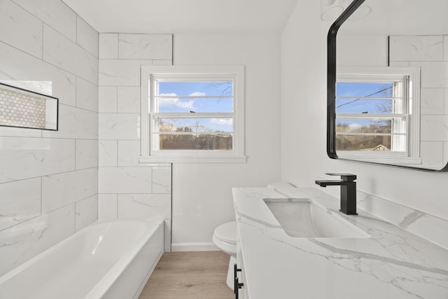 full bathroom featuring baseboards, wood finished floors, toilet, and a healthy amount of sunlight