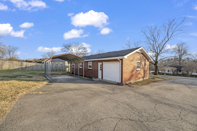 garage featuring a carport, fence, and driveway