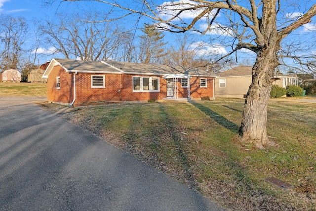 ranch-style house with driveway, brick siding, and a front lawn