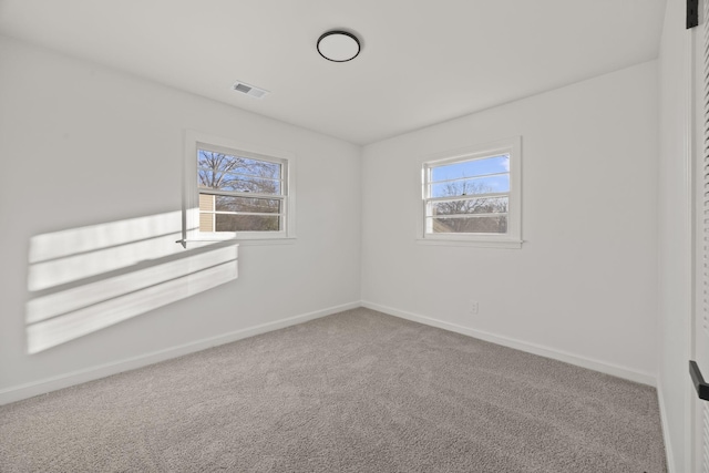 spare room with baseboards, carpet, visible vents, and a healthy amount of sunlight