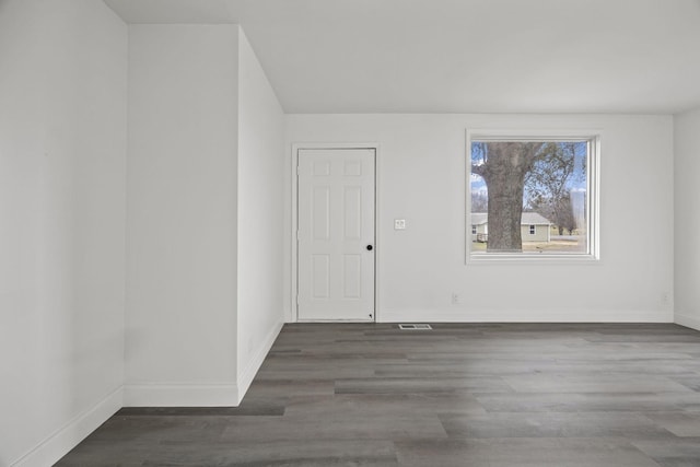 empty room featuring wood finished floors, visible vents, and baseboards