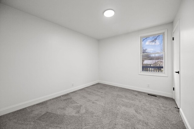 empty room featuring carpet flooring, visible vents, and baseboards