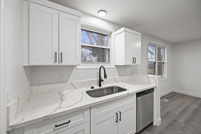 kitchen featuring light stone counters, wood finished floors, a sink, white cabinets, and dishwasher