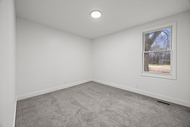 unfurnished room featuring carpet, visible vents, and baseboards