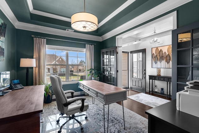 office featuring a notable chandelier, wood finished floors, visible vents, ornamental molding, and a raised ceiling