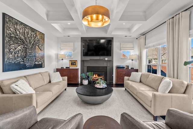 living area with beam ceiling, a fireplace, ornamental molding, wood finished floors, and coffered ceiling