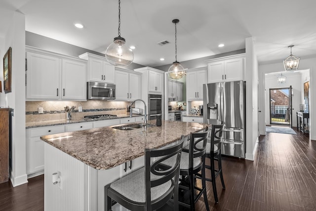 kitchen featuring tasteful backsplash, visible vents, appliances with stainless steel finishes, dark wood-type flooring, and a sink